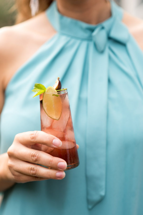 woman holding a cocktail with figs and lime