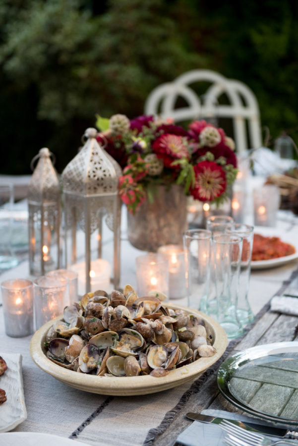 table setting with lanterns, flowers and clams in a bowl