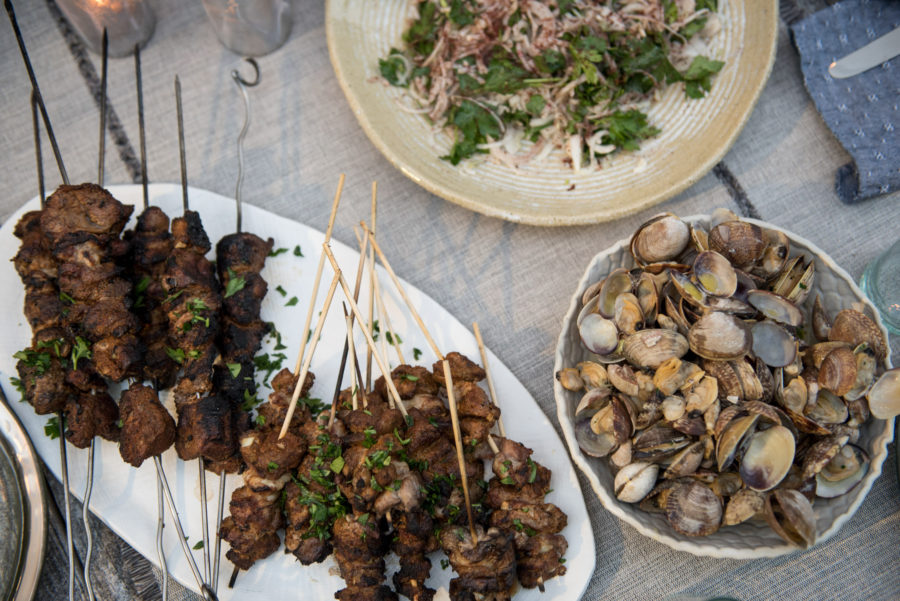 grilled lamb on skewers, clams in a bowl, and salad